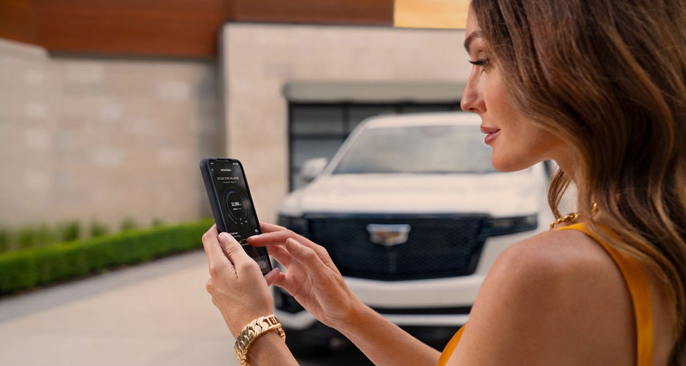 lady checking her mobile with a Cadillac vehicle background | Corwin Cadillac Reno in Reno NV